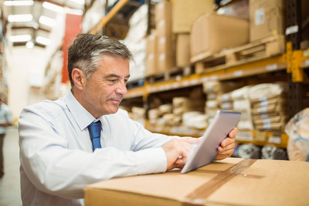 warehouse manager working on tablet pc in a large warehouse