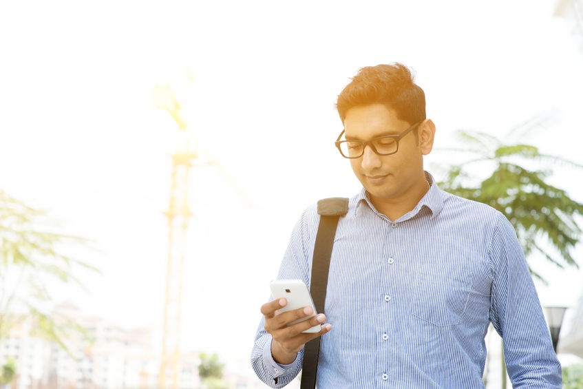sian indian business people texting using smartphone while walking to office, modern urban sunrise view.