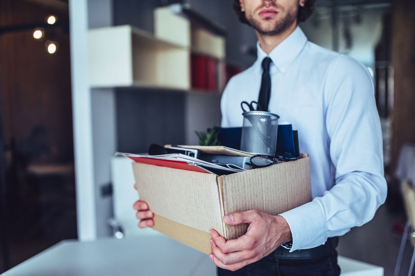 young handsome businessman in light modern office with carton box. last day at work. upset office worker is fired.