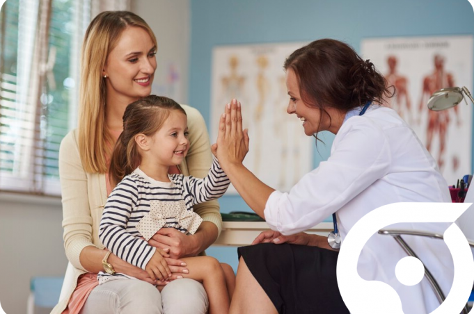 A young girl gives a high five to a smiling female doctor while her mother looks on.